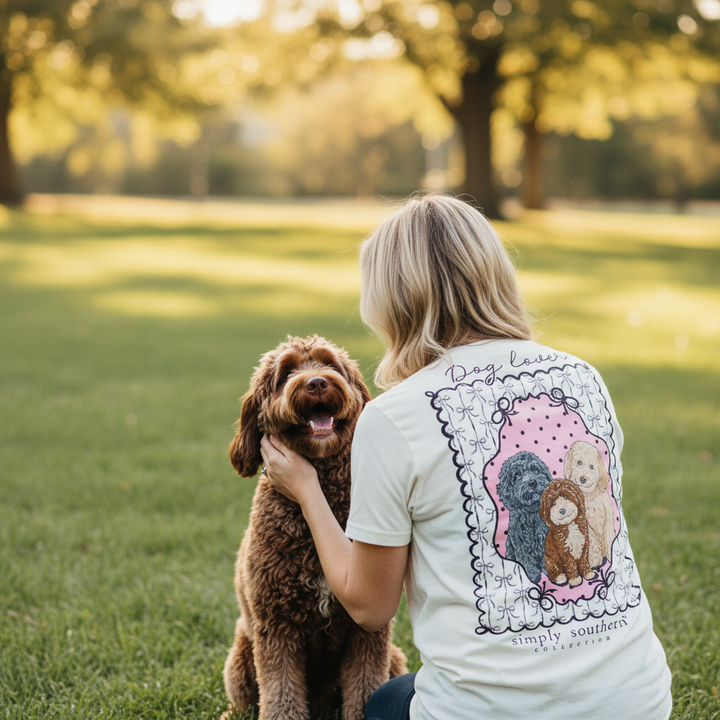 Woman bending down petting labradoodle wearing doodle dog shirt